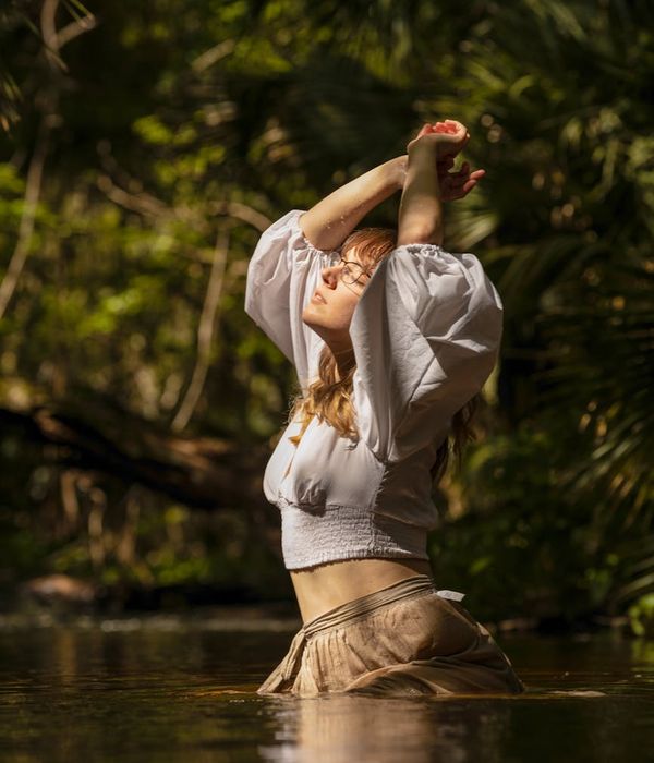 A calm woman meditating in a lotus pose surrounded by a mint green glow.